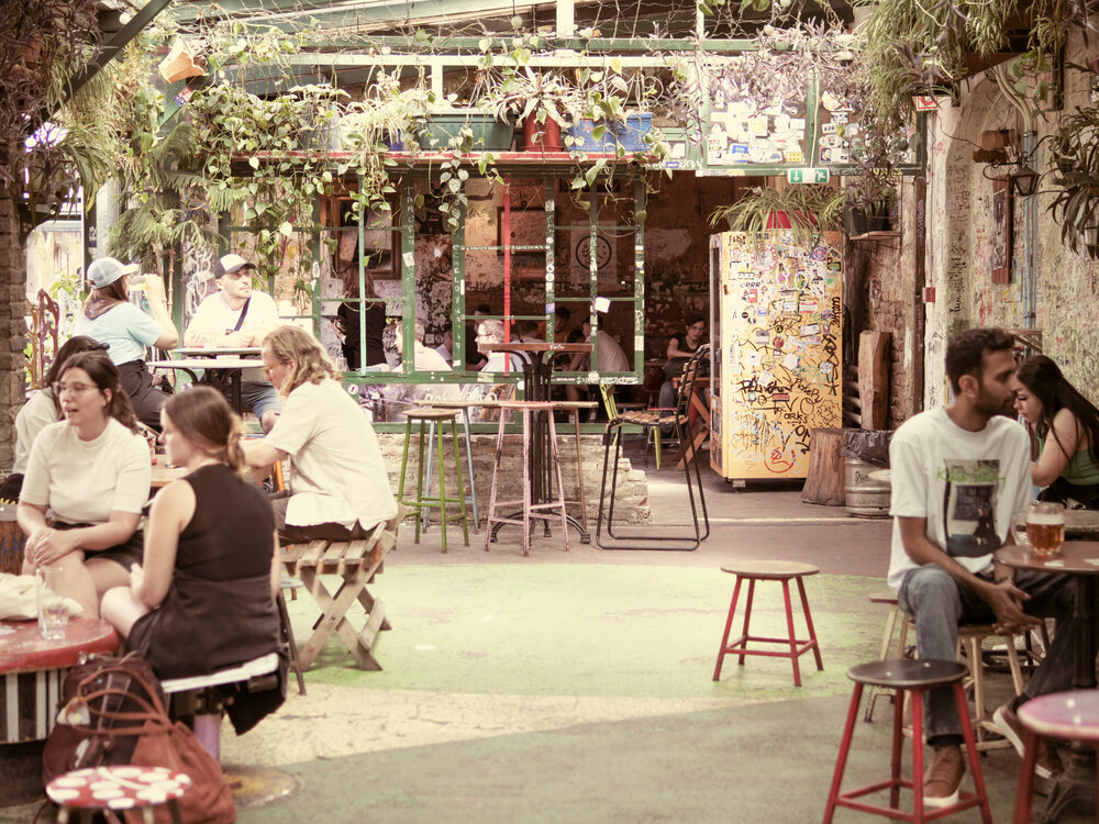 Plant-filled, graffiti-covered courtyard of a Budapest ruin bar with people at tables