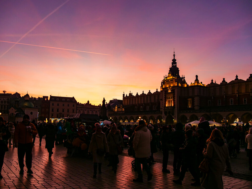 Crowds in silhouette on Krakow's main square at sunset with the lit Cloth Hall, Poland