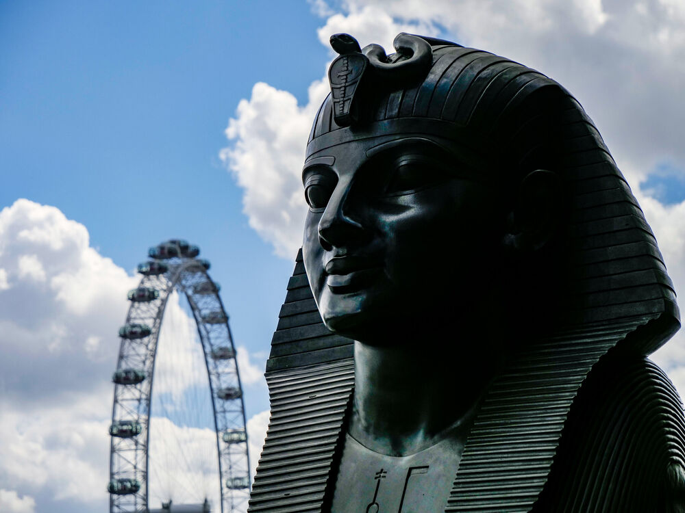 Bronze sphinx statue on Victoria Embankment in profile with the London Eye behind, London
