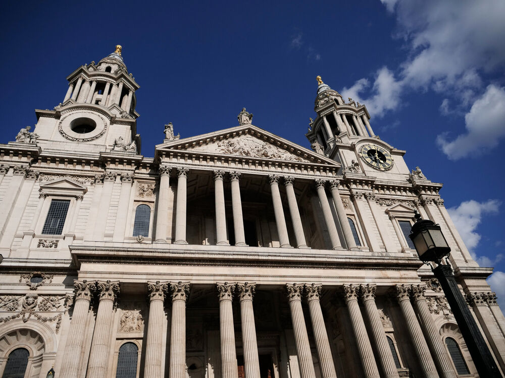 The west front of St Paul's Cathedral with its two towers and clock against deep blue sky, London