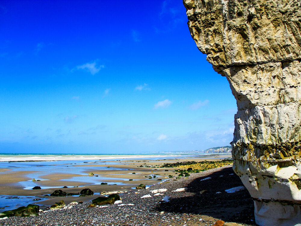 White chalk cliffs above a pebble and sand beach at low tide on the Normandy coast
