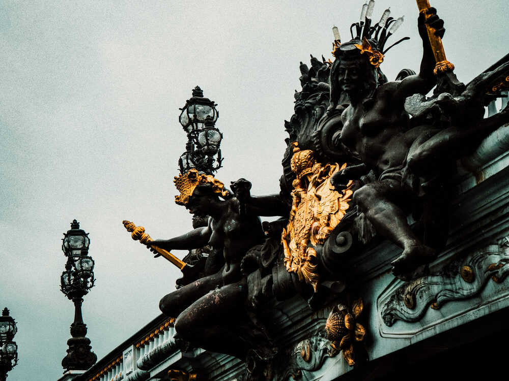 Gilded bronze sculptures on the Pont Alexandre III against a grey sky, Paris