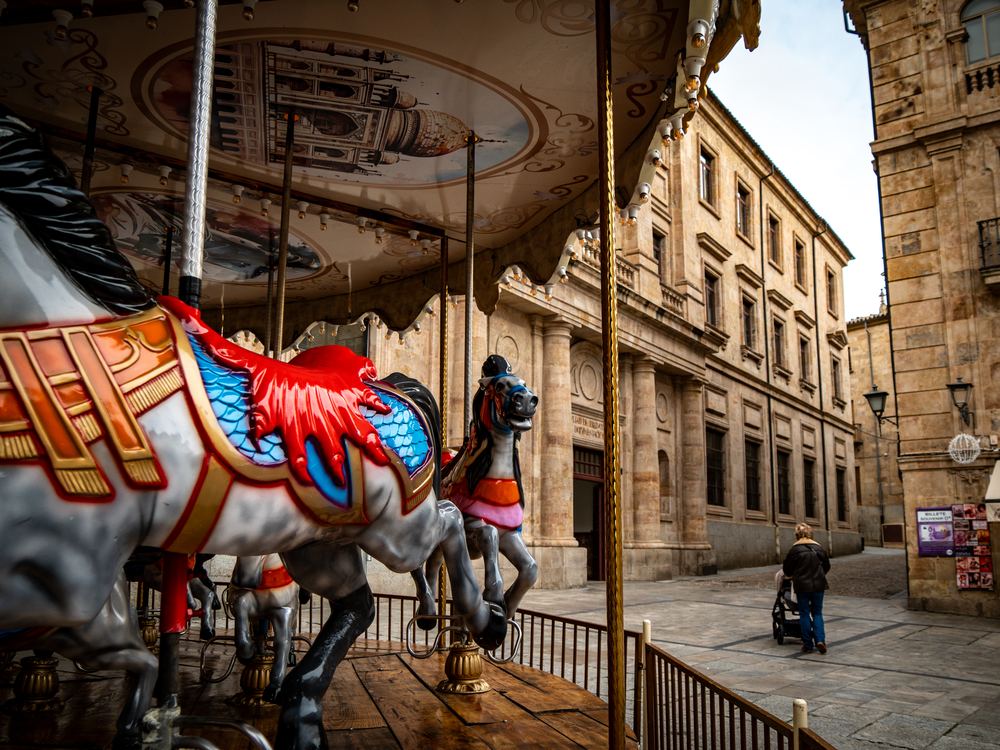 Painted carousel horse with Salamanca's old university buildings behind
