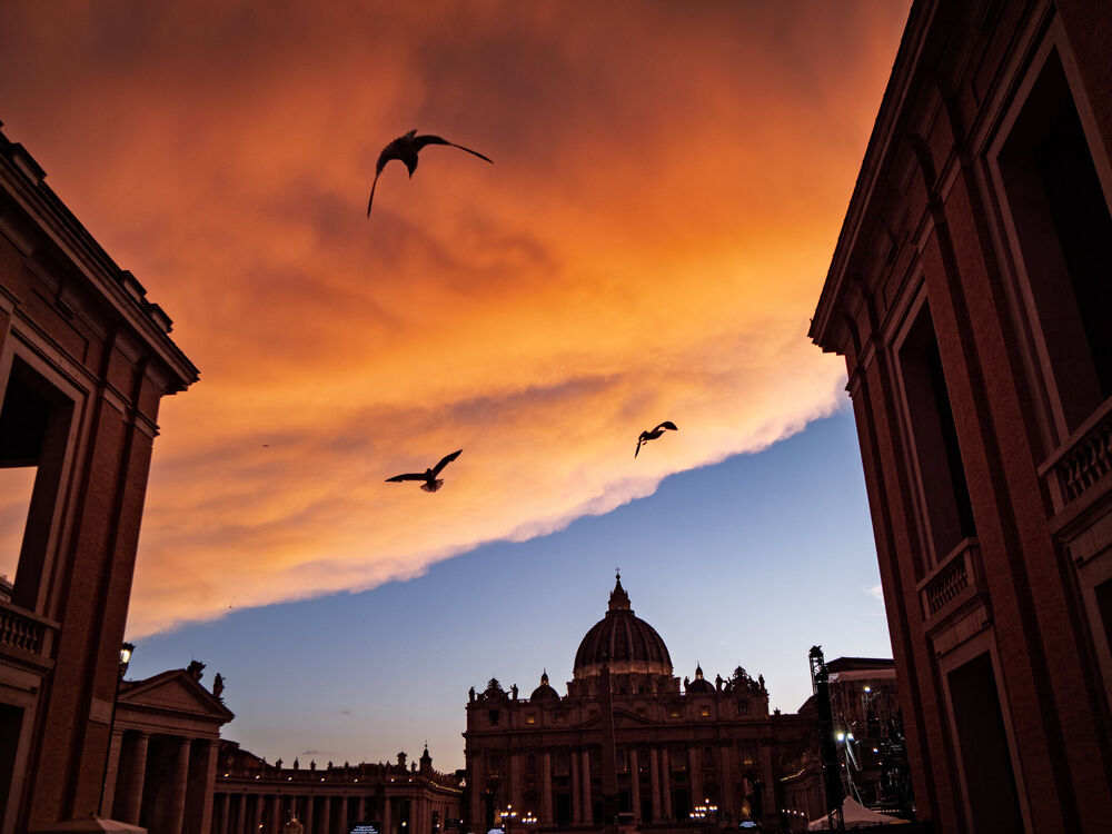 Gulls silhouetted against a fiery sunset sky above St Peter's Basilica, Vatican City