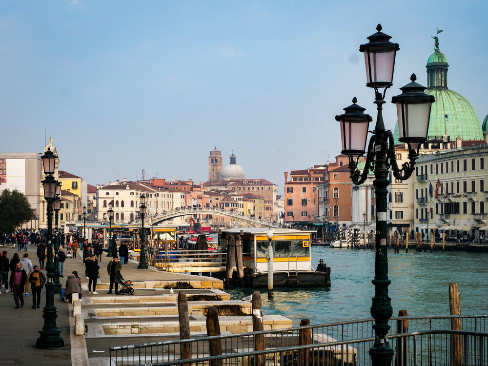The Grand Canal waterfront by Venice's railway station with ornate lampposts, the Scalzi bridge and a green church dome